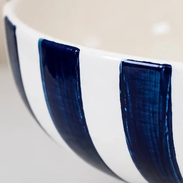 Close-up of glossy deep blue stripes and the white interior of a ceramic decorative bowl