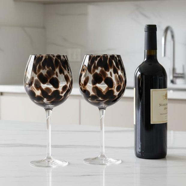 Brown Tortoise Print Wine Glasses - Set of Two, two tortoiseshell-patterned wine glasses beside a bottle