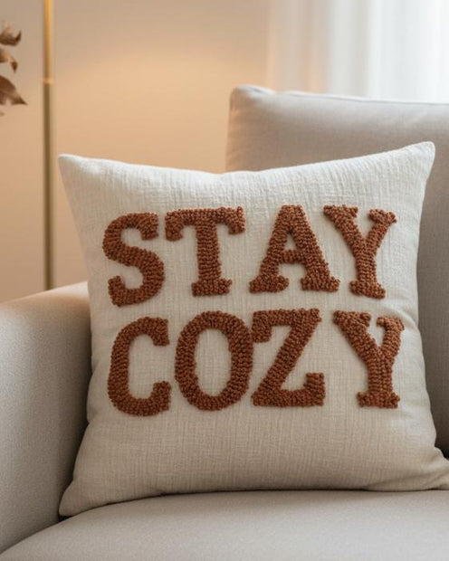 Stay Cozy Rusty Orange Cushion Cover, cream cushion with rusty orange Stay Cozy lettering on a sofa