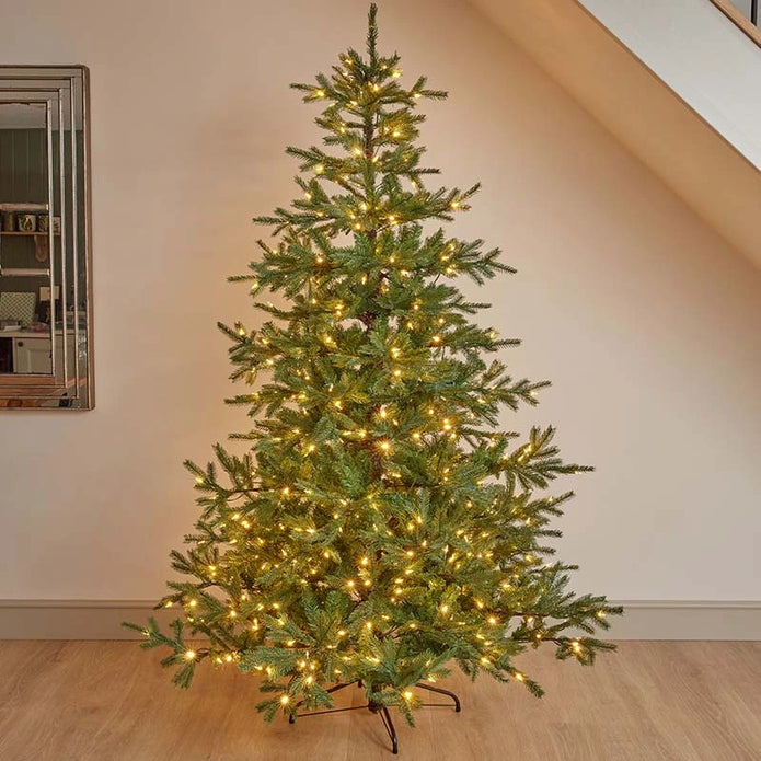 7ft InLit King Conifer with green branches and warm lights, standing in a room.