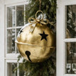 Gold Metal Hanging Bell With Cut Out Stars, close-up of a gold bell and star cutouts beside a window