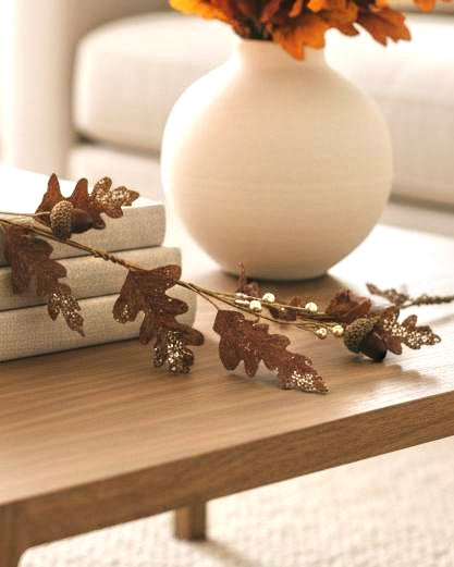 Brown Acorn Leaf Garland – Rustic Autumn Foliage Decoration, brown oak leaves and acorns draped beside books and a vase