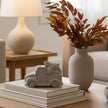 Two silver-toned vintage pickup truck figurines carrying bundles of Christmas trees, displayed on a light gray surface against a white paneled background.