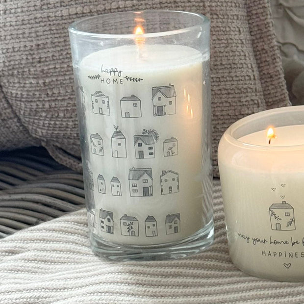 Beige Moments Tall Candle - Home, tall house-patterned candle burning beside a smaller candle