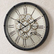 Black frame mechanical skeleton clock by Heaven Sends showing intricate gears and open design on a white background.
