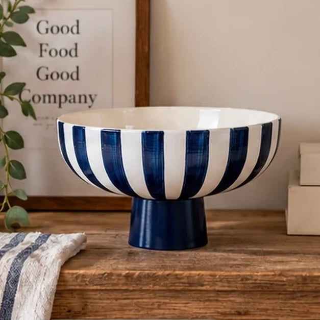 Empty deep blue and white striped ceramic footed bowl on a wooden kitchen counter