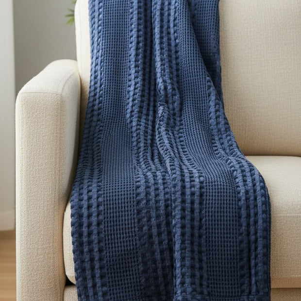 Navy Blue Waffle Throw, navy blue waffle-knit throw draped over a cream armchair