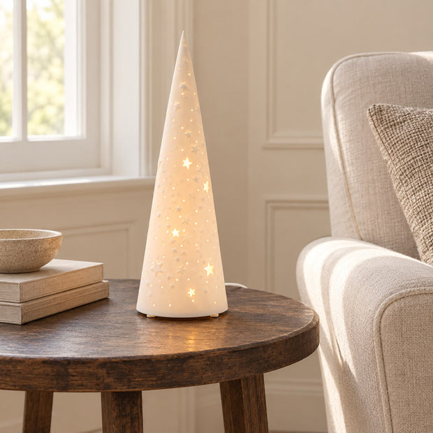White Porcelain Christmas Tree Lamp, single glowing cone tree lamp on a round side table