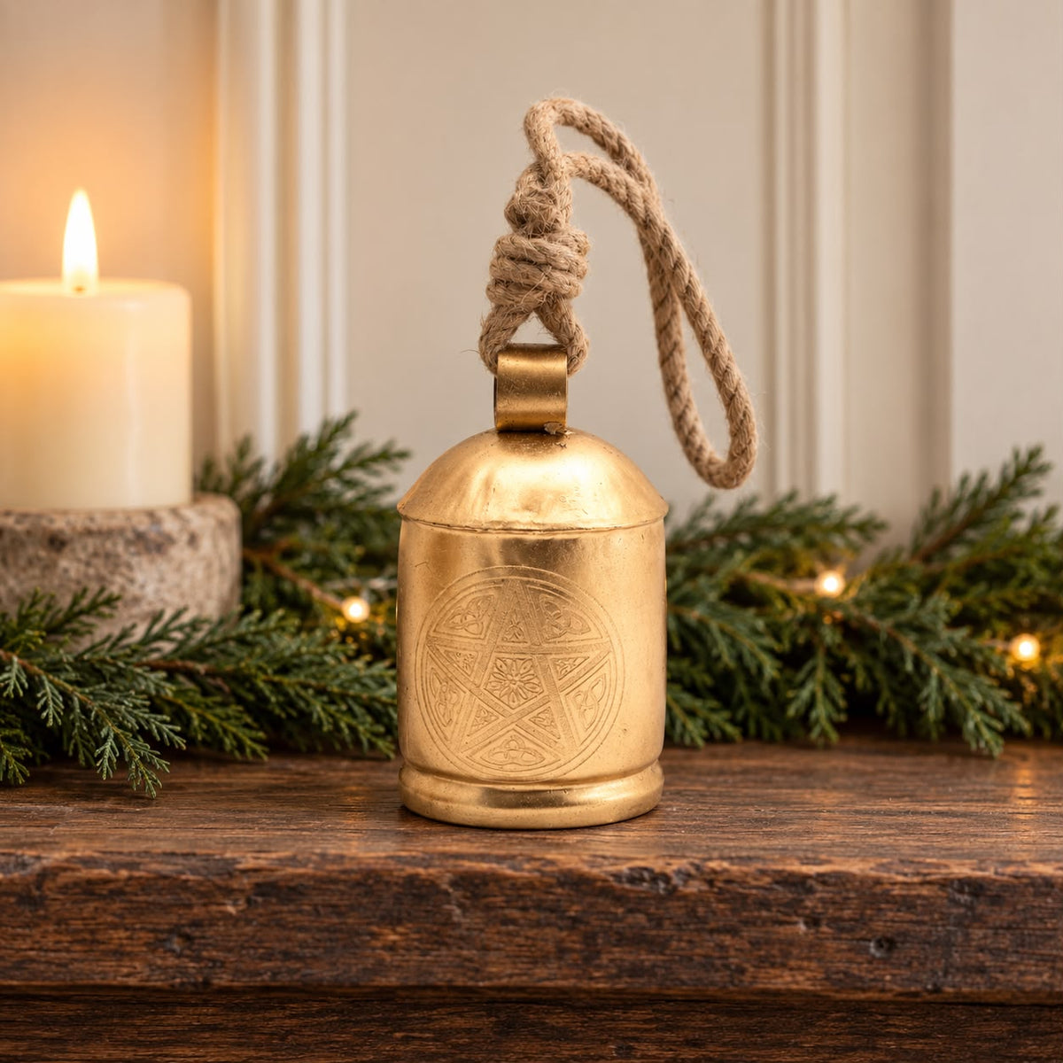 Large Brass Gold Cow Bell On Rope, gold-coloured bell on a rustic mantel beside greenery
