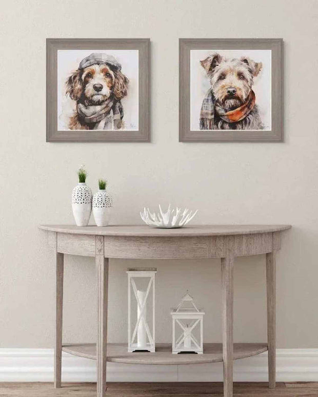 Two framed dog portraits above a wooden console table with decorative items.