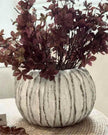 Decorative vase with purple foliage on a wicker table
