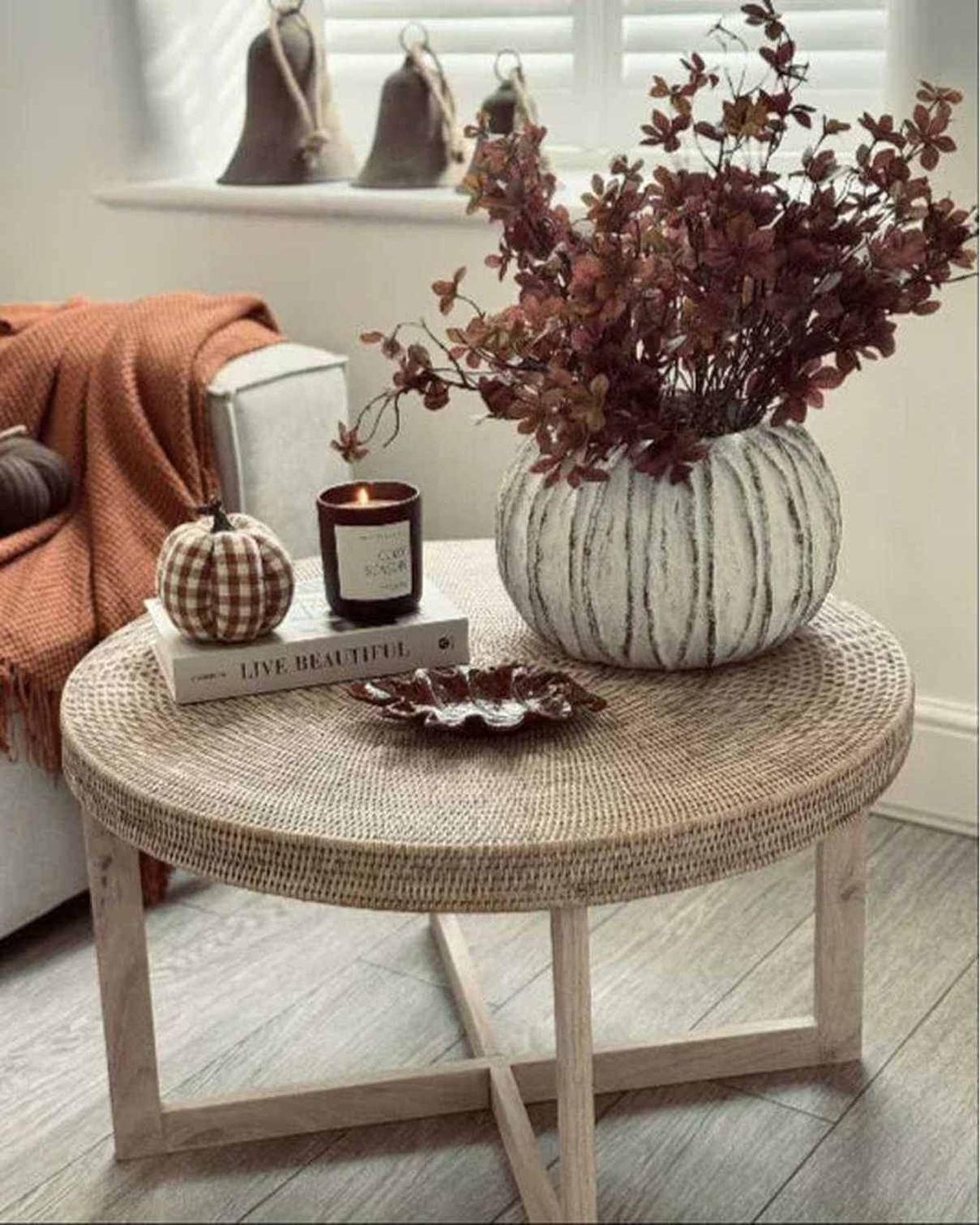 Round woven coffee table with decorative items in a cozy living room.