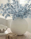 White vase with light blue flowers on a textured surface
