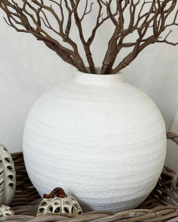 White textured vase with branches and small pumpkins on a neutral background