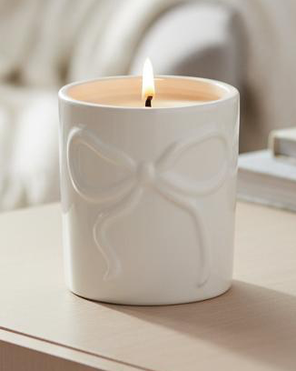 Cream Bow Candle Pot, close-up of the raised bow and lit candle
