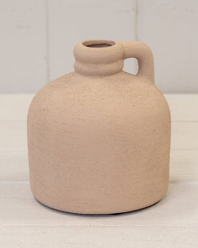 Beige ceramic vase with a handle on a white surface and background