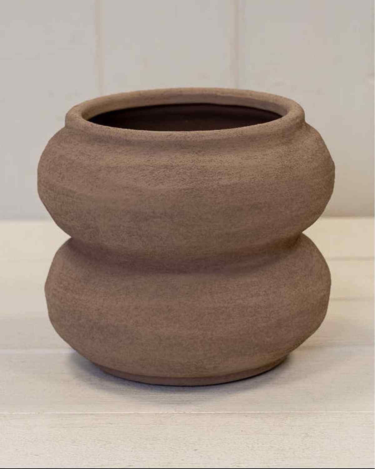 Brown ceramic pot on a white surface with a light gray background