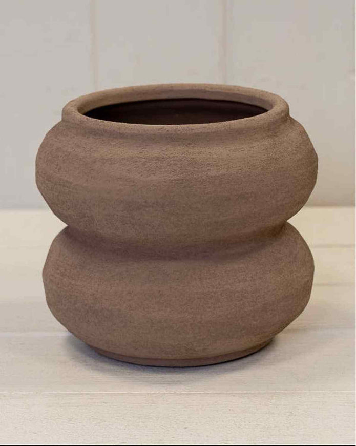 Brown ceramic pot on a white surface with a light gray background