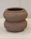 Brown ceramic pot on a white surface with a light gray background