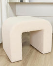 Cream boucle arched foot stool from Starlight Express, showcasing soft textured fabric and elegant curved design.
