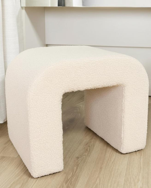 Cream boucle arched foot stool from Starlight Express, showcasing soft textured fabric and elegant curved design.