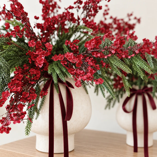 Burgundy gypsophila stems with spruce in a cream vase