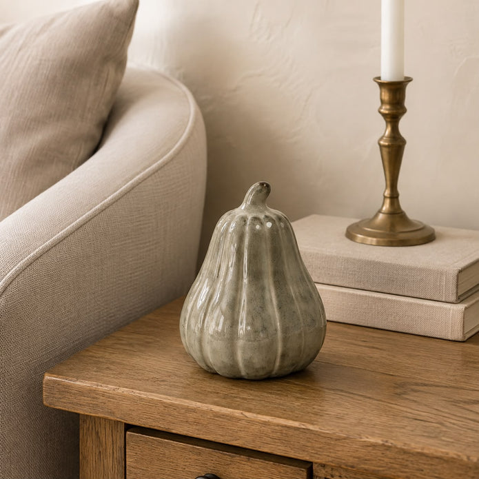 Beige Mottle Ceramic Pumpkin Decoration, mottled ceramic squash beside books and a taper candle