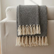 Black Recycled Yarn Blanket Throw, dark knitted throw with cream tassels over a sofa