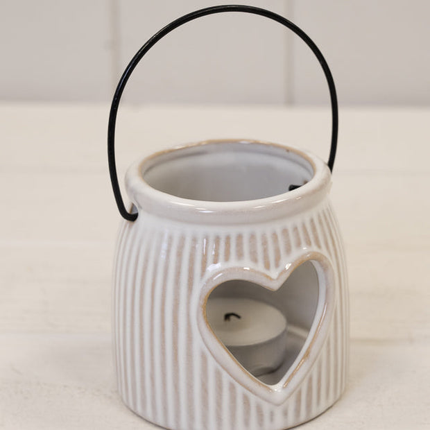 Natural Ceramic Tealight Holder With Cut Out Heart, ribbed ceramic heart lantern with handle on a pale surface
