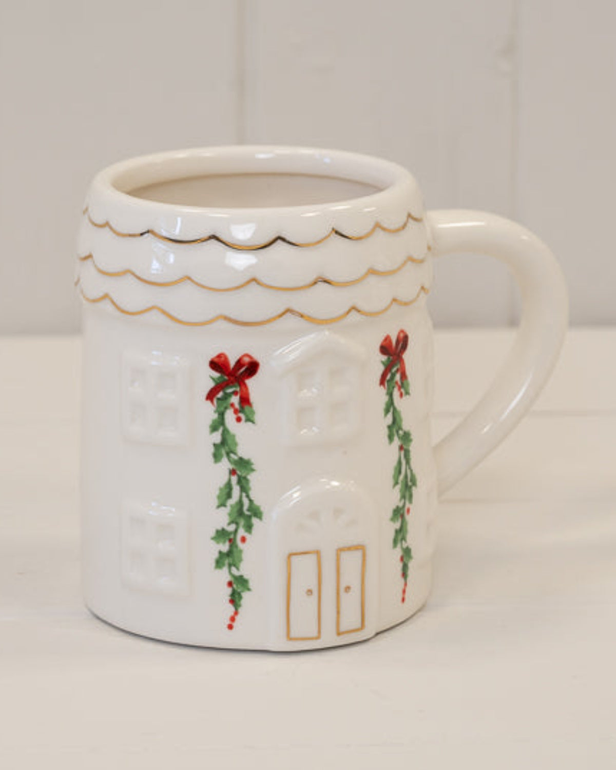 Cosy White Christmas House Mug with green garlands and red bows