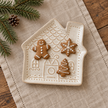 Cream ceramic gingerbread house plate lying flat with three festive biscuits