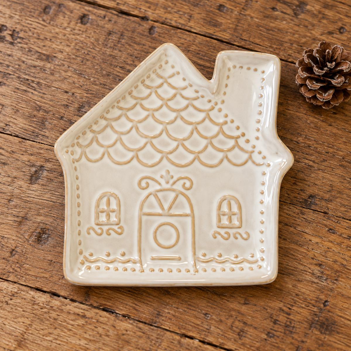 Close-up of cream ceramic gingerbread house plate lying flat, showing raised glazed detail