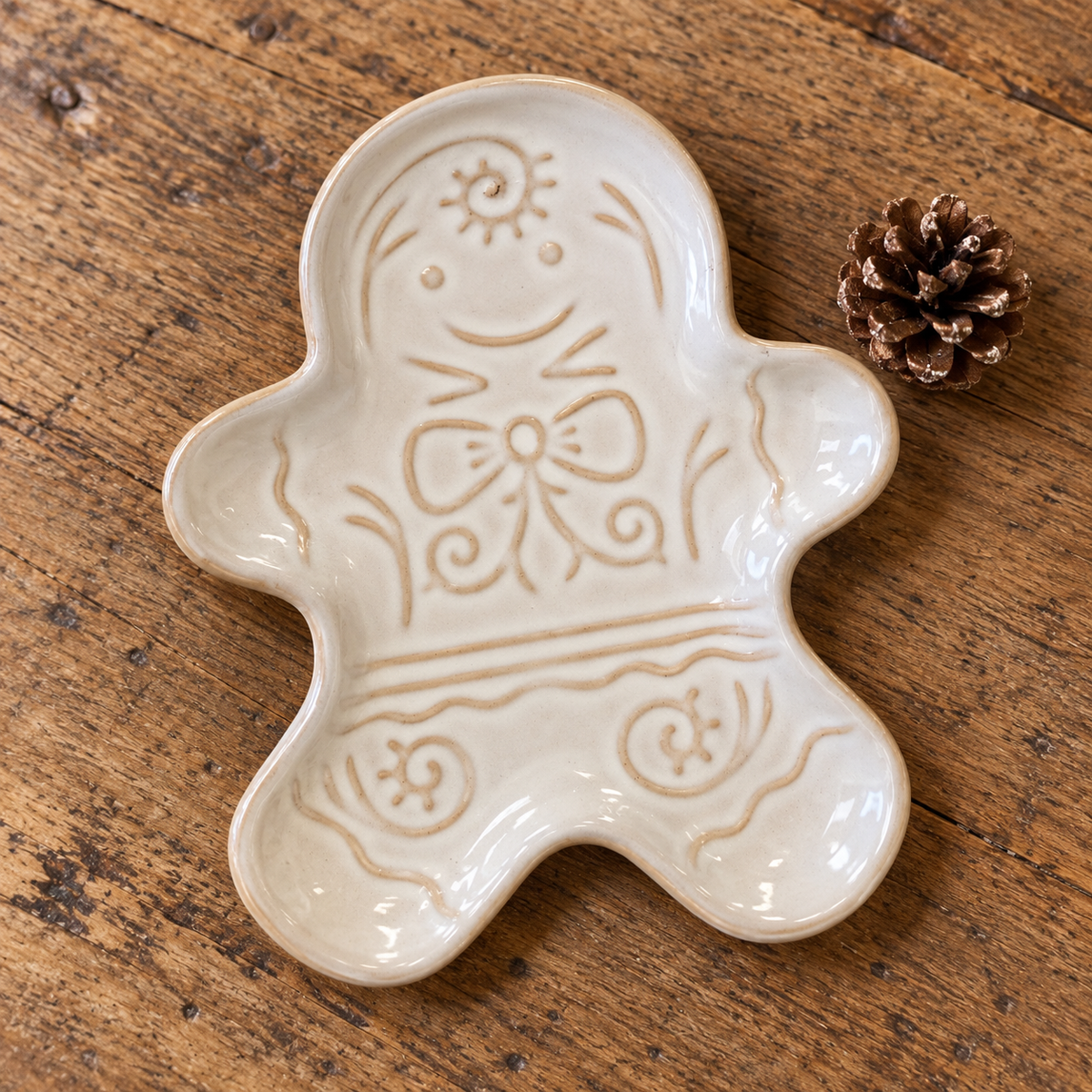 Close-up of cream ceramic gingerbread man plate lying flat, showing raised glazed detail