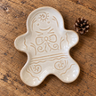 Close-up of cream ceramic gingerbread man plate lying flat, showing raised glazed detail