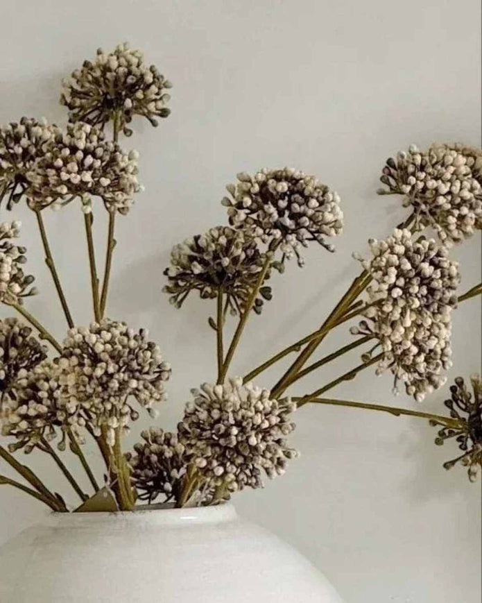 Decorative dried flowers in a white vase against a light background