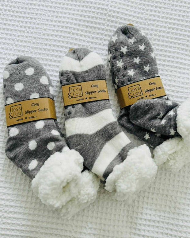 Three pairs of gray and white patterned socks with fuzzy texture on a textured surface.