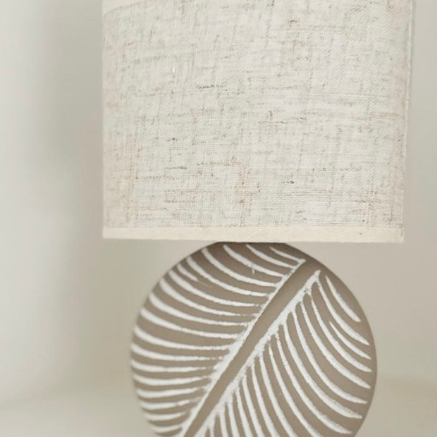 Stone Leaf Table Lamp with Beige Linen Shade, leaf-patterned stone lamp with a beige linen shade