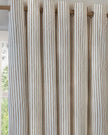 Riva Home yard natural striped blackout eyelet curtains hanging in a room, soft furnishings with black and white stripes.