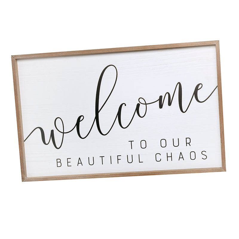 Welcome to Our Beautiful Chaos sign with black lettering on a white panel in a natural wood frame.