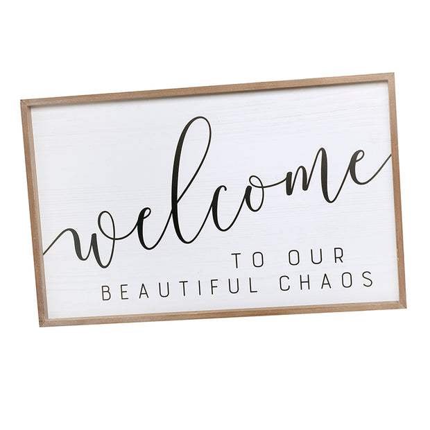 Welcome to Our Beautiful Chaos sign with black lettering on a white panel in a natural wood frame.