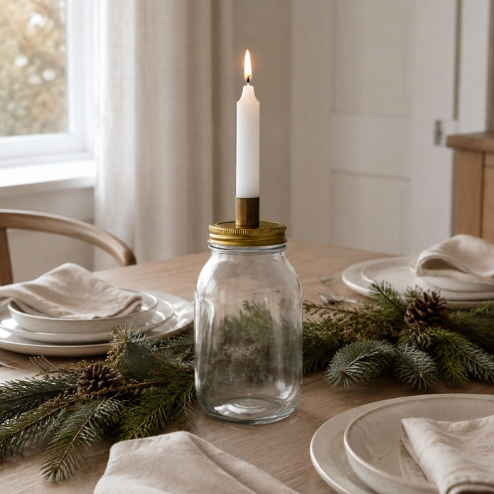 Ivory Candles In A Glass Storage Jar And Holder, clear storage jar with brass lid holding a lit taper on a dining table