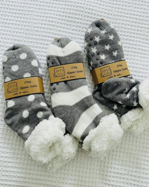 Three pairs of gray and white patterned socks with fuzzy texture on a textured surface.