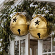 Gold Metal Hanging Bell With Cut Out Stars, two gold bells hanging from snowy branches