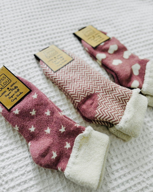 Three pairs of pink socks with different patterns on a textured surface