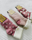 Three pairs of pink socks with different patterns on a textured surface