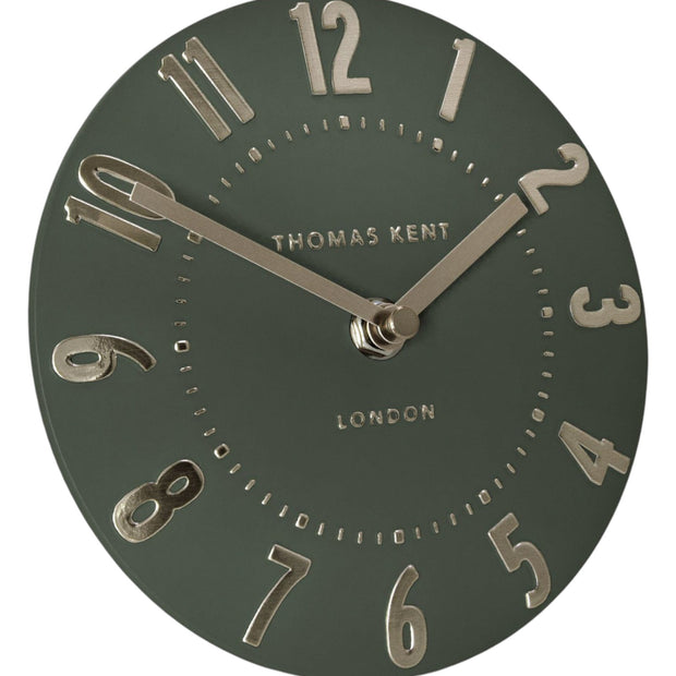 Olive green Thomas Kent 6-inch Mulberry mantle clock with black hands and white dial, mounted on a wooden surface.