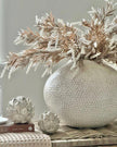Decorative vase with dried plants on a textured surface