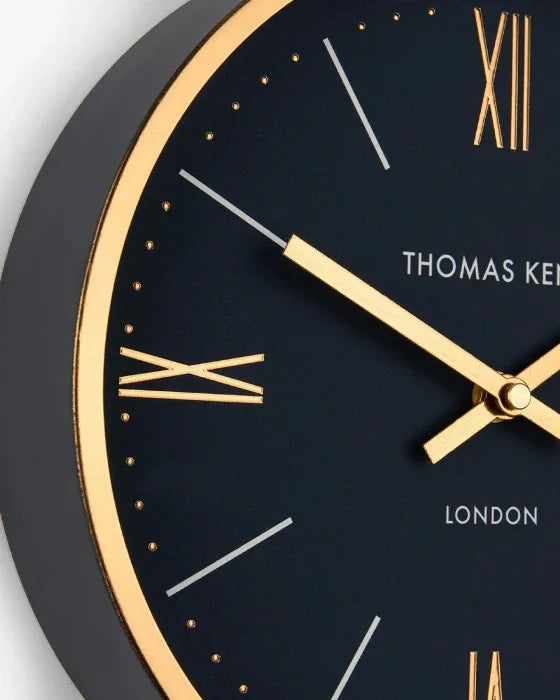 Black clock with gold hands and details, featuring the brand 'Thomas Kent'.