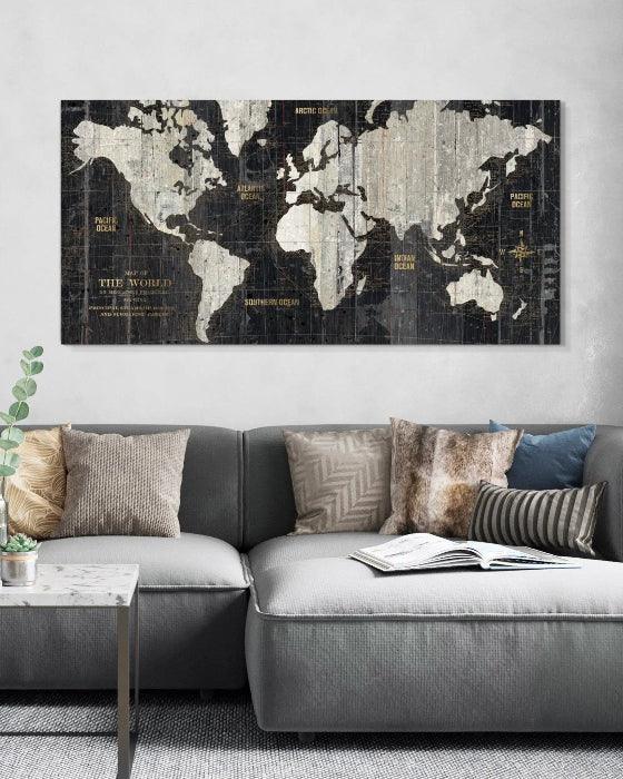 World map canvas on a wall above a gray sofa with decorative pillows.