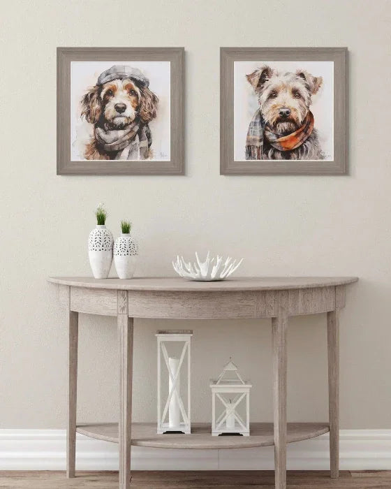 Two framed dog portraits above a wooden console table with decorative items.